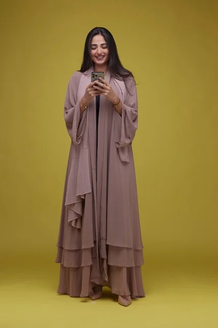 Saudi Woman Using Smartphone on Solid Yellow Background