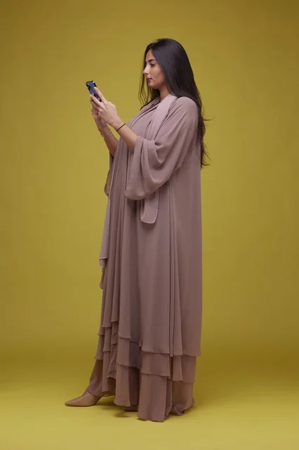 Saudi Woman Using Smartphone on Solid Yellow Background
