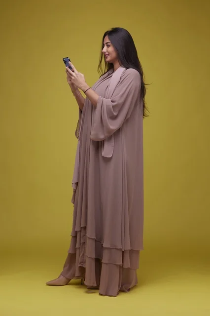 Saudi Woman Using Smartphone against Yellow Background