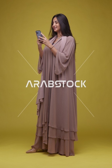 امرأة سعودية تستخدم الهاتف الذكي خلفية صفراء