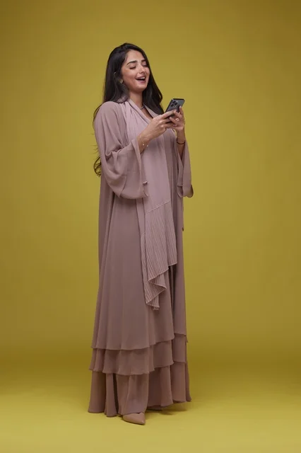 Saudi Woman in Abaya Using Smartphone on Yellow Background