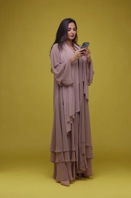 Saudi Woman Using Smartphone on Yellow Background