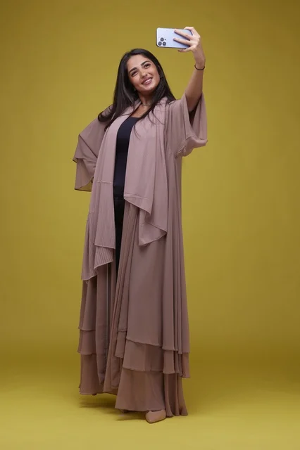 Saudi Woman Taking Selfie in Brown Abaya Yellow Background