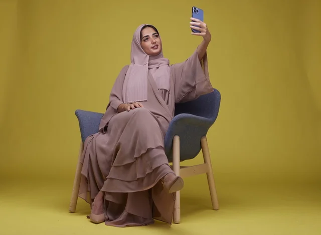 Saudi Woman in Abaya Taking Selfie Yellow Background