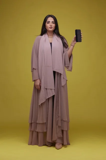Saudi Woman Holding Smartphone Against Yellow Background