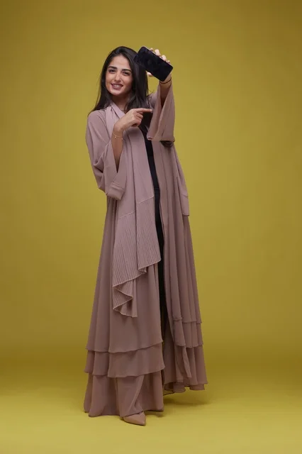 Saudi Woman Pointing at Smartphone Screen on Yellow Background