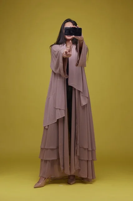 Saudi Woman Holding Smartphone Against Yellow Background