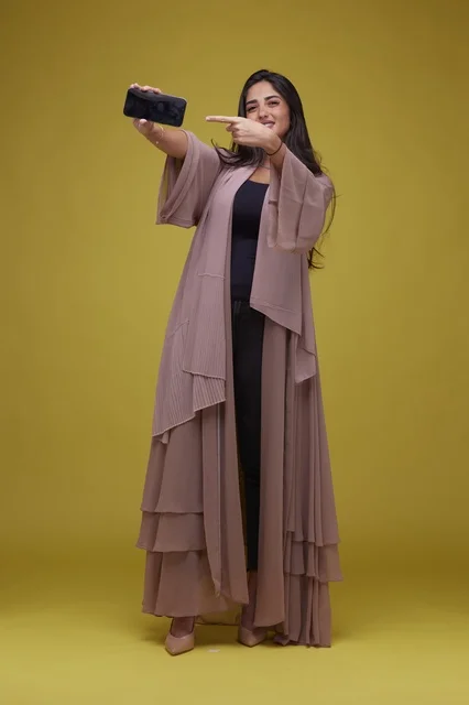 Saudi Woman Holding Smartphone Screen on Yellow Background