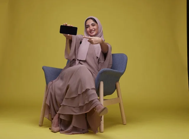 Saudi Woman Holding Smartphone on Yellow Background