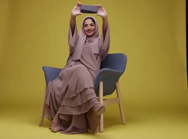 Saudi Woman with Smartphone on Yellow Studio Background