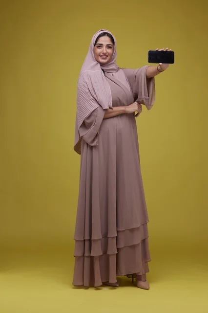 Saudi Woman Holding Blank Smartphone on Yellow Background