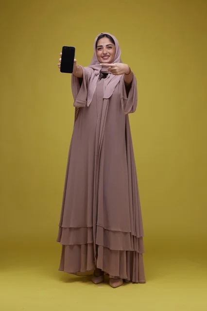 Smiling Saudi Woman Pointing to Blank Smartphone Screen