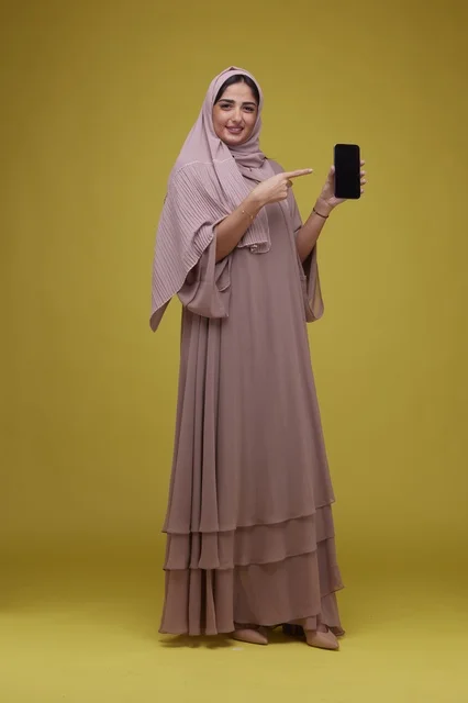 Smiling Saudi Woman Pointing at Blank Smartphone Screen