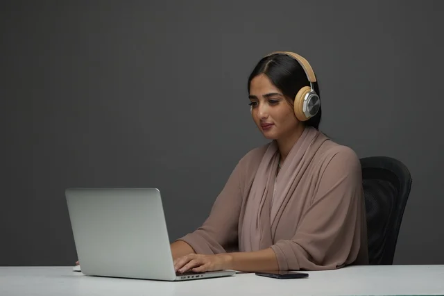 Saudi Woman Working on Laptop with Headphones