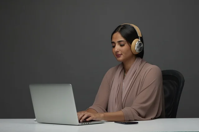 امرأة سعودية تعمل على لابتوب مع سماعات