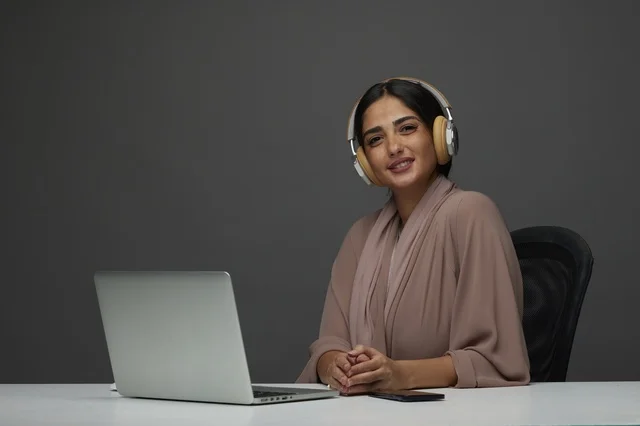 Saudi Woman Wearing Headphones While Working on Laptop