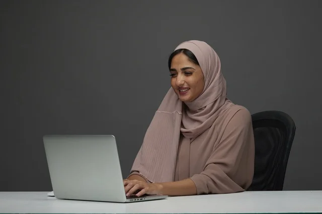 امرأة سعودية تعمل على لابتوب في مكتب عصري
