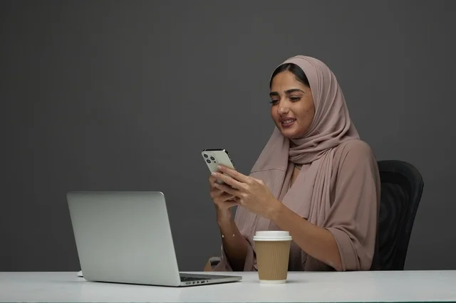 سيدة أعمال سعودية تستخدم الهاتف الذكي في مكتب العمل
