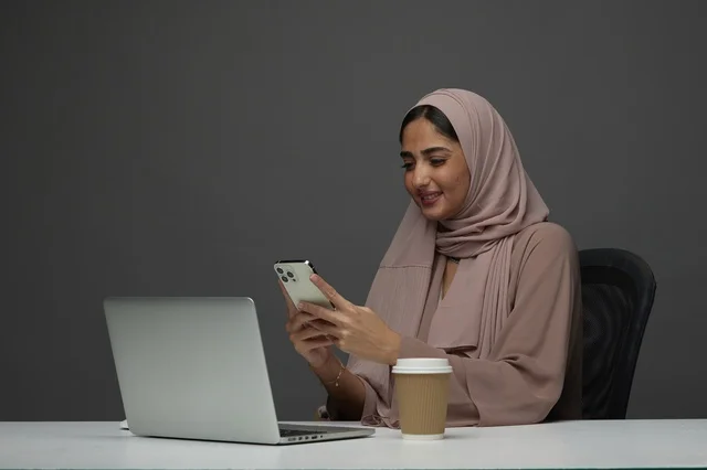 Saudi Businesswoman Using Smartphone at Office Desk