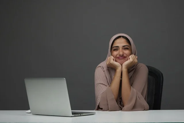 Smiling Saudi Businesswoman at Office Desk with Laptop