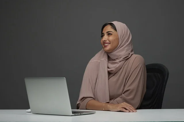 Smiling Saudi Businesswoman with Laptop at Office Desk