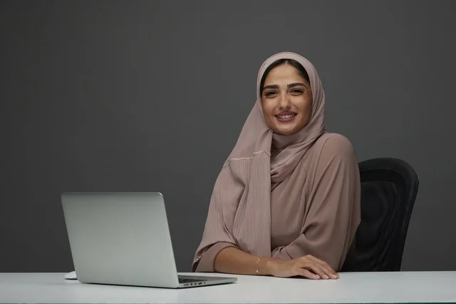 Smiling Saudi Businesswoman at Desk with Laptop