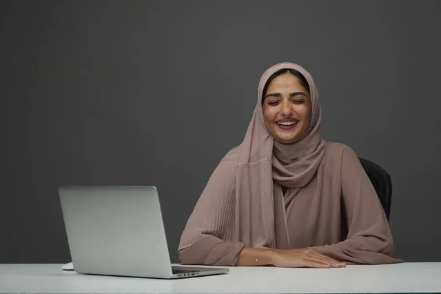 Saudi Businesswoman with Laptop in Office Smiling