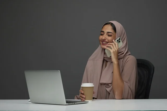 سيدة أعمال سعودية في مكتب حديث مع لابتوب وهاتف