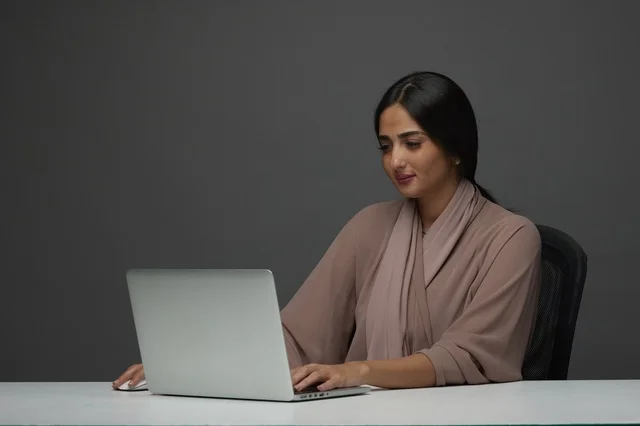 سيدة أعمال سعودية تعمل على لابتوب في مكتب عصري