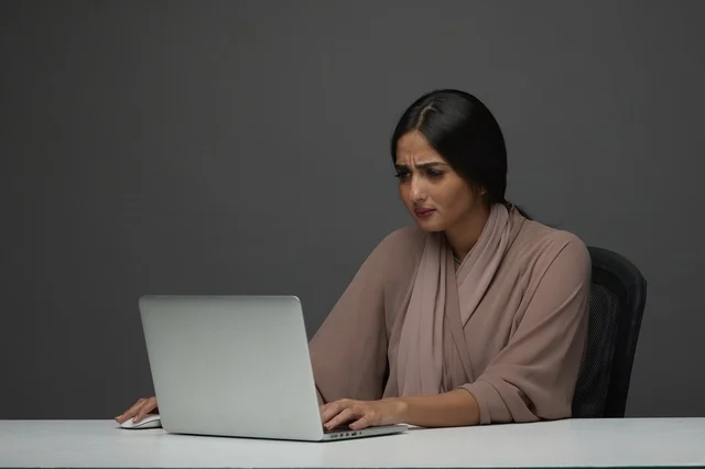 سيدة أعمال سعودية قلقة تعمل على اللابتوب في المكتب