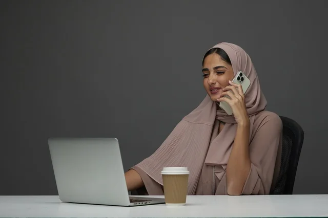 Saudi Businesswoman on Phone Call with Laptop and Coffee