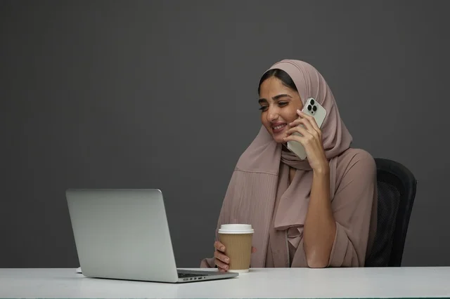 Saudi Businesswoman Using Laptop and Phone at Desk