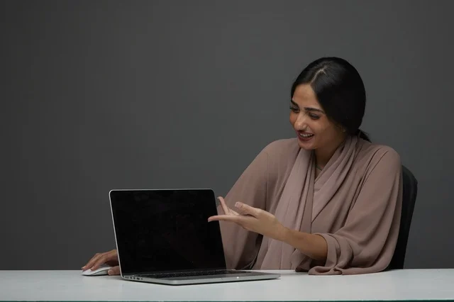 Saudi Woman Pointing at Laptop Screen in Office