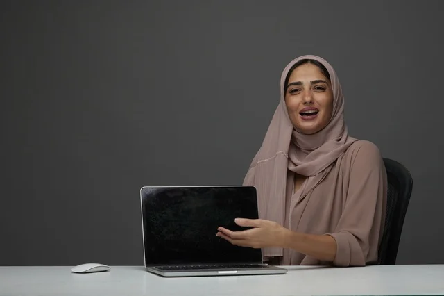 Saudi Businesswoman Presenting Laptop on Office Desk