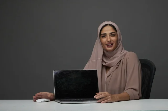 سيدة أعمال سعودية مع لابتوب بخلفية رمادية
