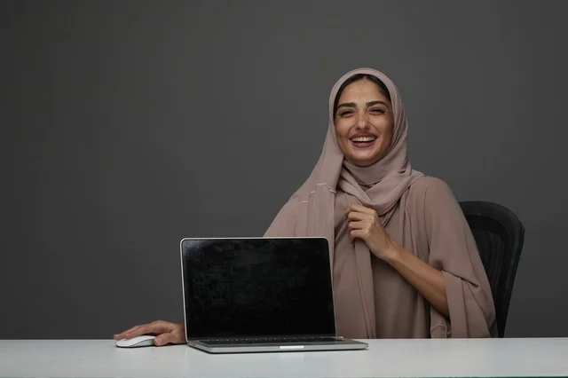 Saudi Businesswoman with Laptop Smiling at Desk