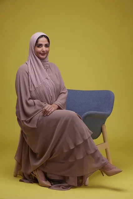 امرأة سعودية بعباءة أنيقة خلفية صفراء