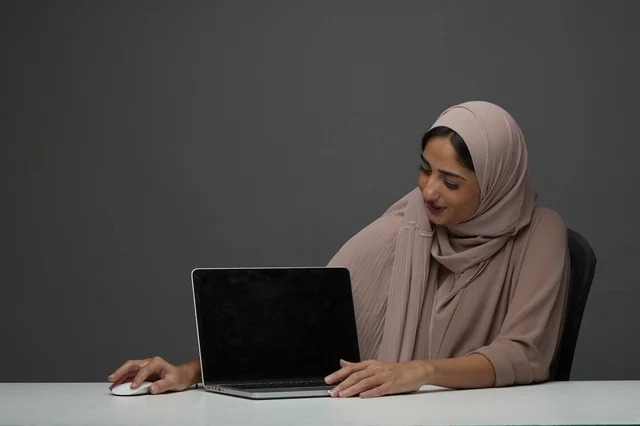 Saudi Businesswoman Presenting Laptop on Grey Background