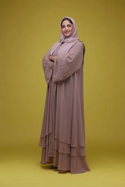 امرأة سعودية بعباءة موف على خلفية صفراء