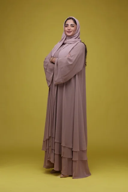 Saudi Woman in Mauve Abaya Standing on Yellow Background
