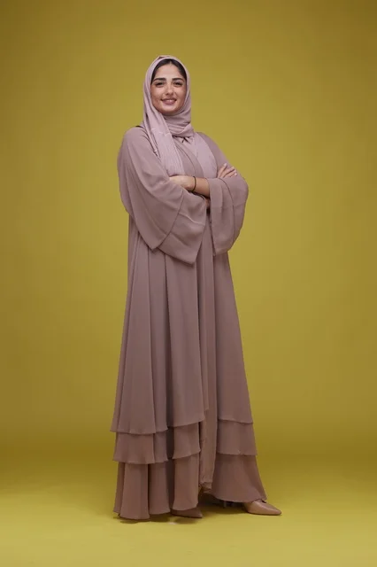 Saudi Woman in Mauve Abaya Standing on Yellow Background