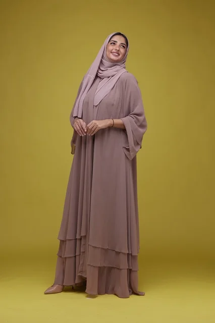 امرأة سعودية بعباية أرجوانية على خلفية صفراء