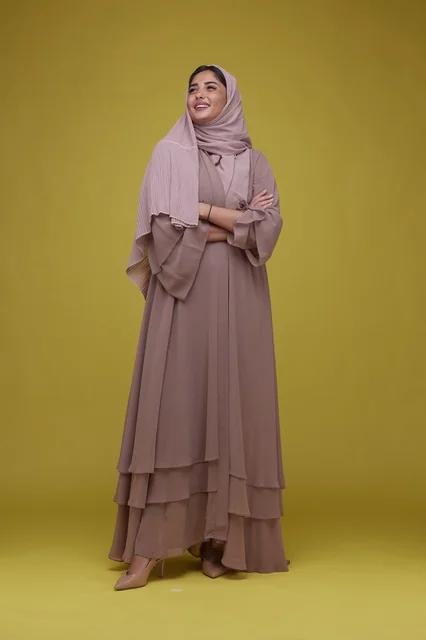 Saudi Woman in Mauve Abaya Standing on Yellow Background
