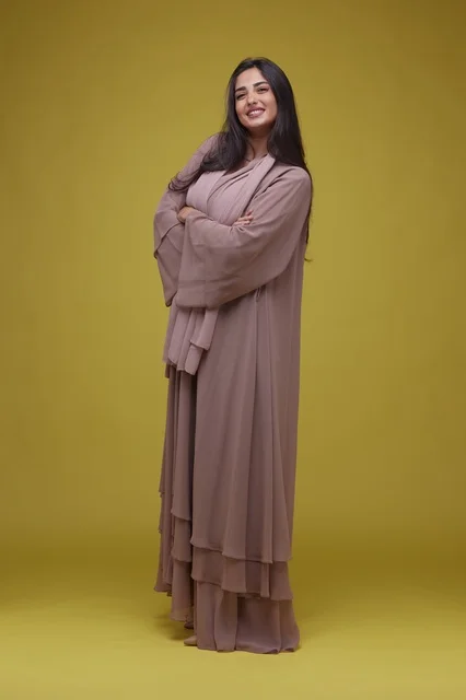 Smiling Saudi Woman Wearing Abaya on Yellow Background
