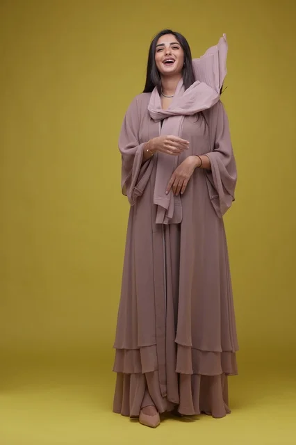 Laughing Saudi Woman in Pink Abaya on Yellow Background