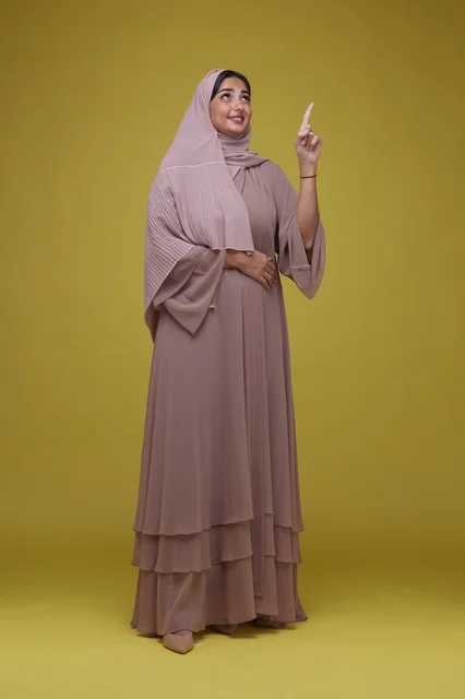 Saudi Woman in Abaya Pointing Up on Yellow Background