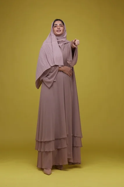 Saudi Woman in Pink Abaya Pointing on Yellow Background
