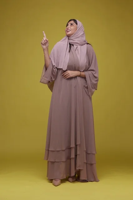 Saudi Woman in Mauve Abaya Pointing Up on Yellow
