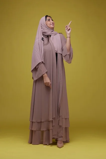 Saudi Woman Pointing Up Against Yellow Background