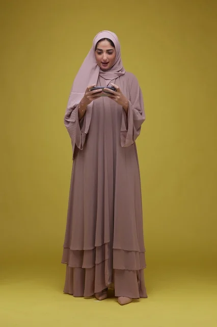 Saudi Woman Playing Mobile Game on Yellow Background